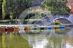 View of colorful docked boats by the bridge over a lake in Jardim Mario Soares park