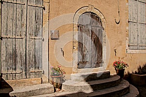 View of colorful house and door with flowers and steps, on a street of Lourmarin.