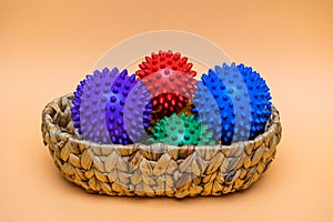 View of colorful spikey balls in a basket over the orange background