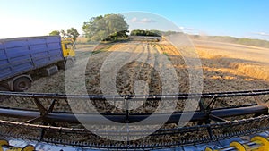 View from combine cabin to farm and agricultural machinery during harvesting. Grain harvester riding through farmland