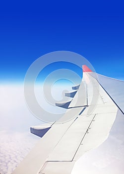 View of a commercial aeroplane from window where you can see the wing which flies above the clouds.