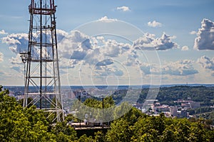 View of communication towers with blue sky, mountain and cityscape background. Top view of the radio tower in the city
