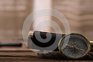 View of compass near telescope and rope cable on wooden table