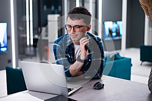 View of concentrated talented skilled male focused on screen of laptop computer, reads necessary information for