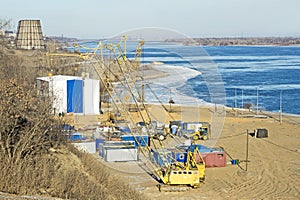 View of the construction site with equipment on the banks of the big river in the offseason. Background