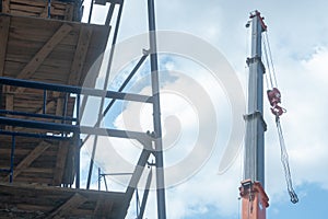 View of the construction site, scaffolding installed around the old building. The boom of the tower crane hangs over the temple