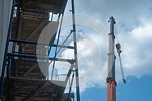 View of the construction site, scaffolding installed around the old building. The boom of the tower crane hangs over the temple