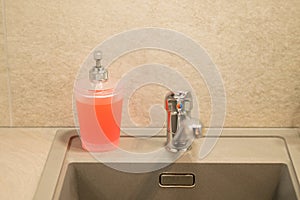 View of a container of liquid soap on a gray kitchen sink, clean house