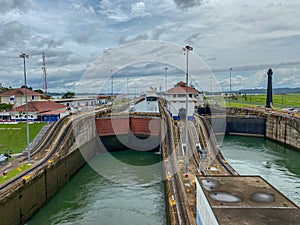 A view of a container ship and two yachts entering the first lock in the Panama Canal from a much lower cruise ship