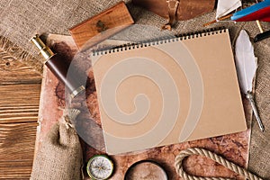 View on copy book near nib, telescope, compass on wooden surface with map and hessian