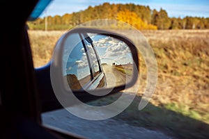 View of a country road through the rearview mirror