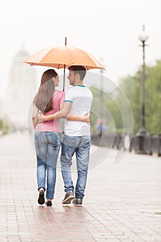View of couple back under umbrella walking.
