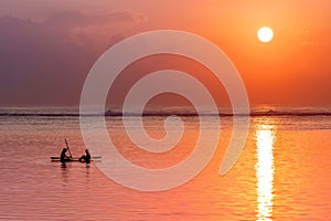 View of a couple leisurely enjoying a paddleboat ride on the beach at sunset