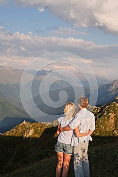 View of a couple watching the sunset on a meadow and the Mountain