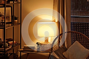 View of a cozy reader`s corner with a table lamp spending warm light