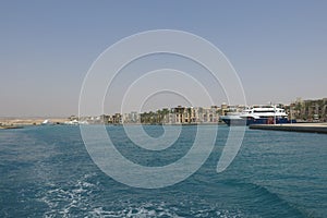 View from cruise ship to Port Ghalib harbor in the Red Sea and modern buildings. Luxury yachts moored at the pier. Turquoise sea