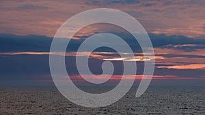 View from cruising ship in calm seas to horizon and sunset glow in sky