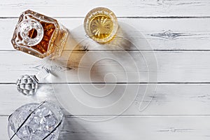 View of a crystal glass and decanter full of golden whisky, and crystal ice bucket, shot from above on a distressed white wooden