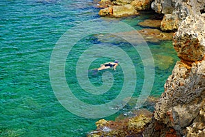 View on the crystal sea water and unknown person swiming on Menorca