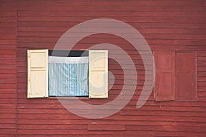 View of curtain and wooden window on red wall of wooden house at countryside.