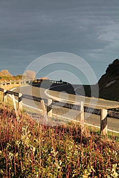 View on curve of empty road on ledge of atlantic coast in sunlight and cloudy sky