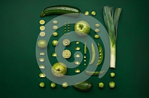 View of cut and fresh green vegetables and fruits in green background