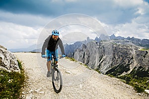 View of cyclist riding mountain bike on trail in Dolomites,Tre C