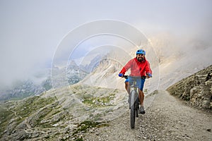 View of cyclist riding mountain bike on trail in Dolomites,Tre C