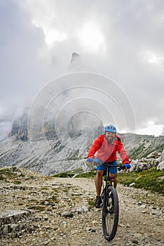 View of cyclist riding mountain bike on trail in Dolomites,Tre C