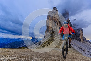 View of cyclist riding mountain bike on trail in Dolomites,Tre C