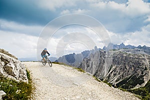 View of cyclist riding mountain bike on trail in Dolomites,Tre C
