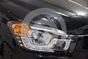 A view of a dark blue car headlight after cleaning and polishing before being sold. Large vehicle lamp with xenon lens. Auto-