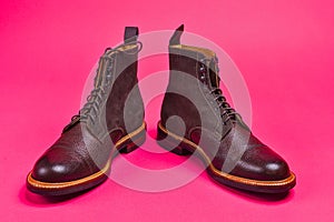 View of Dark Brown Grain Brogue Derby Boots Made of Calf Leather with Rubber Sole Placed Over Pink Burgundy