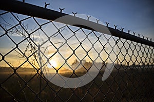 View of dawn from behind a fence