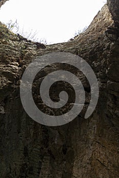 View from a deep cave to the gloomy sky. Close-up. Vertical