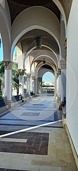 A view of the desert in the distance, through the windows of an Arabian palace, a long hallway in marble, palm and arrangements