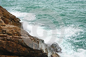 View of deserted rocky coastline and turquoise tropical storm sea with a surf on tropical Koh Chang island in Thailand