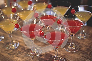 View of different coloured alcohol beverage cocktail drinks setting on bar counter in the night club party, tequila, glasses with