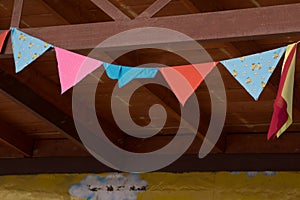 View of different rows of colorful triangular flags in a french city street. Pattern of decorative banners with tree branches in b