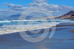 View on difficult to access golden sandy Cofete beach hidden behind mountain range on Fuerteventura, Canary islands, Spain