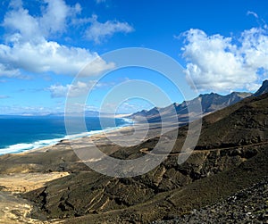 View on difficult to access golden sandy Cofete beach hidden behind mountain range on Fuerteventura, Canary islands, Spain