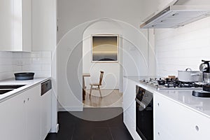 View of dining room at the end of a contemporary white galley kitchen