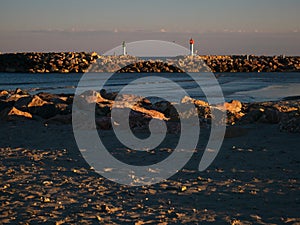 View in the distance of two lighthouses on the coast during a sunset