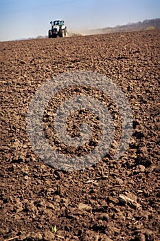 view of distant tractor on skyline with soil on foreground