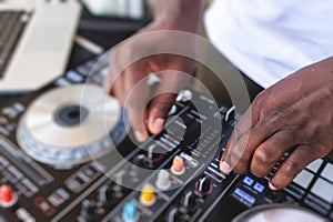 View of Dj mixer and vinyl plate with headphones on a table with african american DJ playing on stage and mixes the track in the