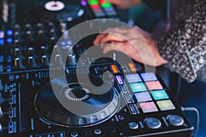 View of Dj mixer and vinyl plate with headphones on a table with DJ playing and mixes the track in the background, during night