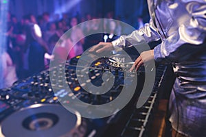 View of Dj mixer and vinyl plate with headphones on a table with female girl DJ playing on stage and mixes the track in the