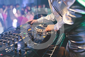 View of Dj mixer and vinyl plate with headphones on a table with female girl DJ playing on stage and mixes the track in the