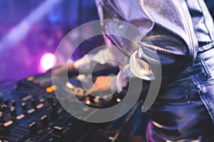 View of Dj mixer and vinyl plate with headphones on a table with female girl DJ playing on stage and mixes the track in the