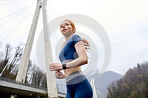 View from down on confident female runner jogger in motion, looking at side